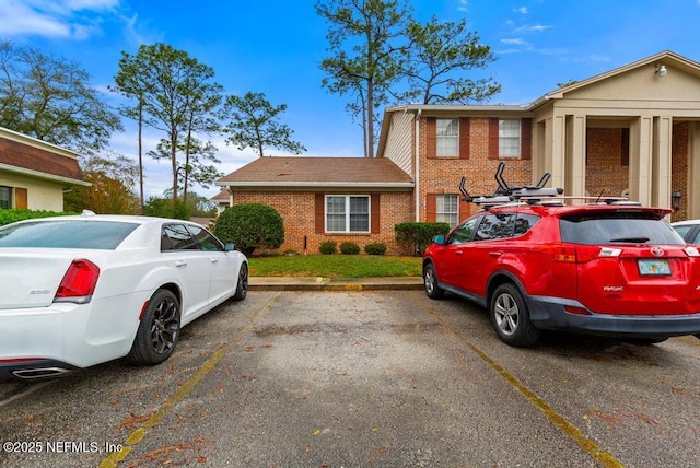 view of front of home with uncovered parking and brick siding