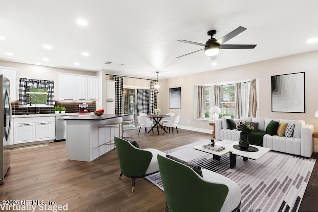 living area with ceiling fan with notable chandelier, recessed lighting, and wood finished floors