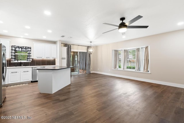 kitchen featuring white cabinets, decorative backsplash, dark wood-style floors, appliances with stainless steel finishes, and a center island