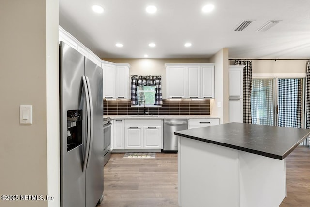 kitchen featuring light wood finished floors, visible vents, white cabinets, appliances with stainless steel finishes, and a sink