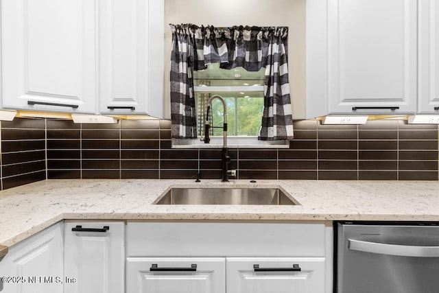 kitchen featuring white cabinets, stainless steel dishwasher, backsplash, and a sink