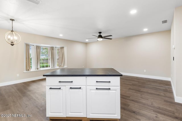 kitchen with dark wood-type flooring, visible vents, white cabinets, baseboards, and dark countertops