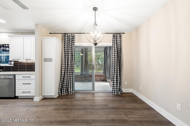 unfurnished dining area featuring a notable chandelier, baseboards, and dark wood-type flooring