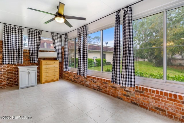 unfurnished room with light tile patterned floors, brick wall, and ceiling fan