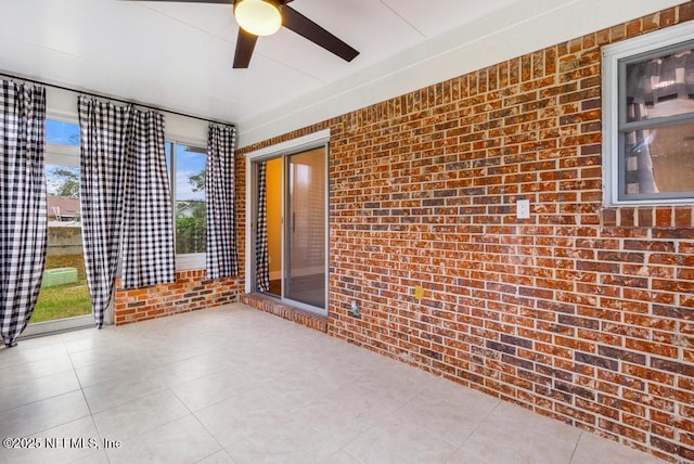 interior space featuring ceiling fan and brick wall