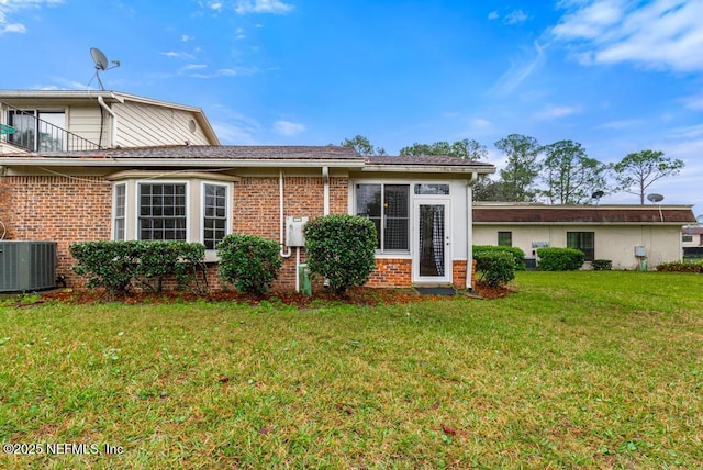 view of front of house featuring central AC unit, a front lawn, and brick siding