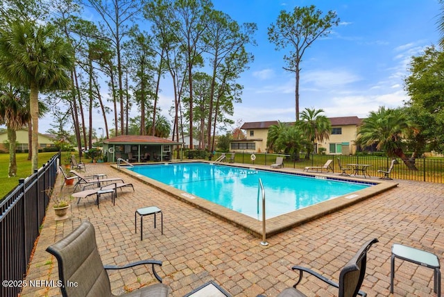 community pool featuring an outbuilding, a patio, and fence