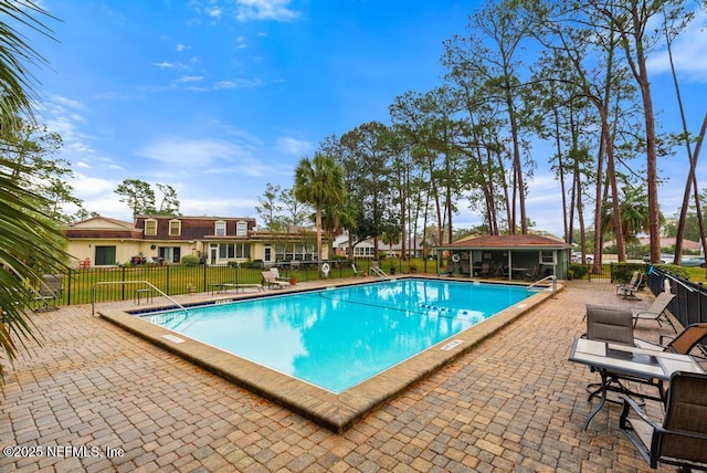 community pool featuring fence, an outdoor structure, and a patio