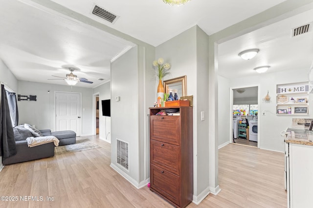 corridor with light hardwood / wood-style floors and washer / dryer