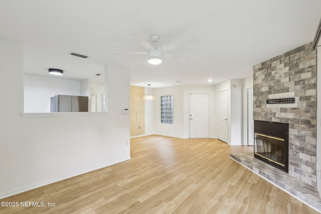 unfurnished living room featuring a fireplace, hardwood / wood-style flooring, and ceiling fan