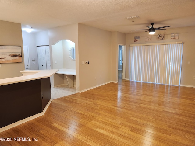 unfurnished living room featuring a textured ceiling, light hardwood / wood-style flooring, and ceiling fan