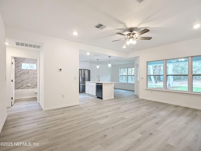 unfurnished living room featuring sink, light hardwood / wood-style floors, and ceiling fan