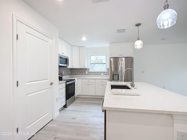 kitchen with white cabinetry, hanging light fixtures, sink, and appliances with stainless steel finishes