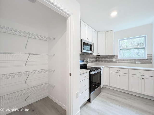 kitchen featuring white cabinetry, appliances with stainless steel finishes, tasteful backsplash, and light wood-type flooring