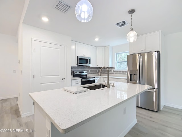 kitchen with sink, appliances with stainless steel finishes, light stone counters, an island with sink, and white cabinets