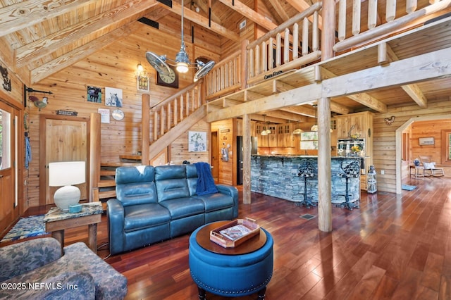 living room with beam ceiling, wooden ceiling, and wooden walls