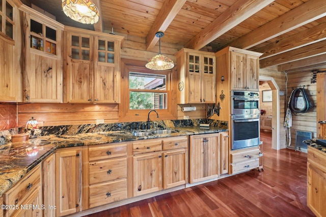 kitchen with beamed ceiling, sink, dark stone countertops, hanging light fixtures, and stainless steel double oven