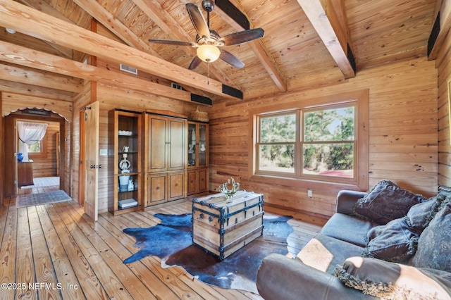 living room with ceiling fan, wooden walls, wood-type flooring, lofted ceiling with beams, and wooden ceiling