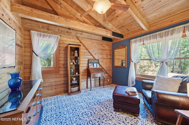 living area featuring a healthy amount of sunlight, wooden walls, lofted ceiling with beams, and wooden ceiling