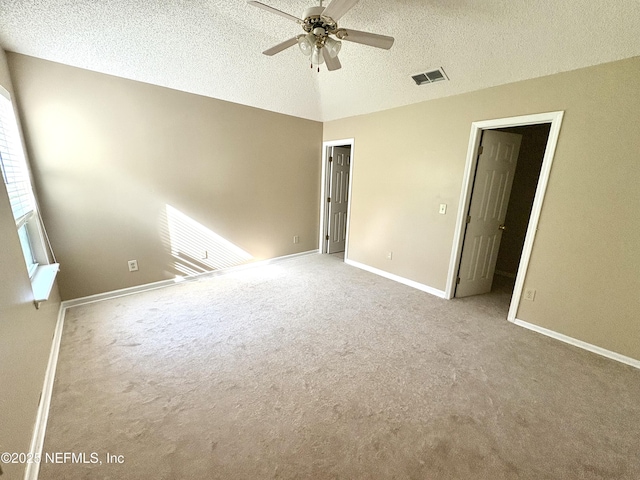 spare room with a textured ceiling, light colored carpet, and ceiling fan