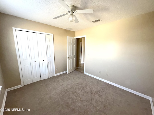 unfurnished bedroom with dark colored carpet, a textured ceiling, a closet, and ceiling fan