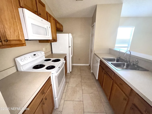 kitchen featuring a textured ceiling, sink, light tile patterned floors, and white appliances