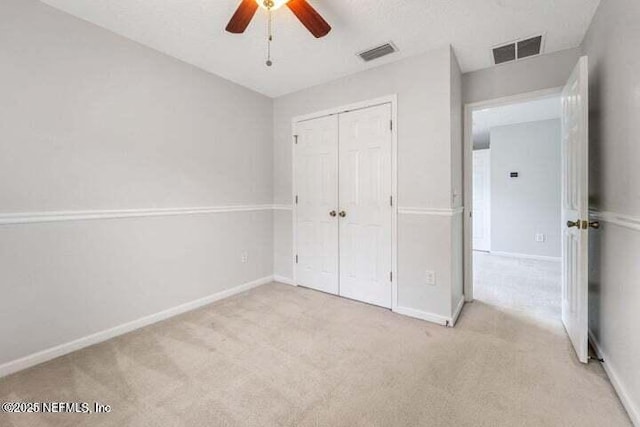 unfurnished bedroom featuring ceiling fan, light carpet, and a closet