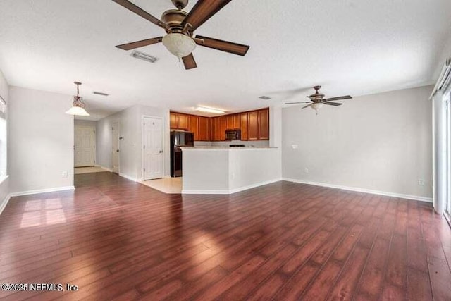 unfurnished living room featuring ceiling fan, dark hardwood / wood-style flooring, and a textured ceiling