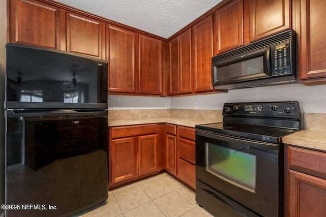 kitchen with black appliances, light tile patterned flooring, and a textured ceiling