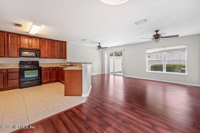 kitchen featuring black appliances, a healthy amount of sunlight, kitchen peninsula, and light hardwood / wood-style flooring