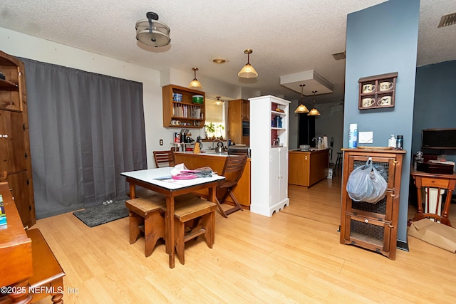 dining space with light wood-type flooring and a textured ceiling