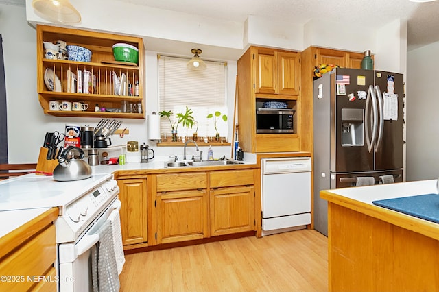 kitchen featuring a textured ceiling, sink, light wood-type flooring, and stainless steel appliances