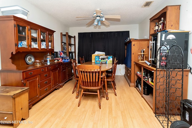 dining room with light wood-type flooring, a textured ceiling, and ceiling fan