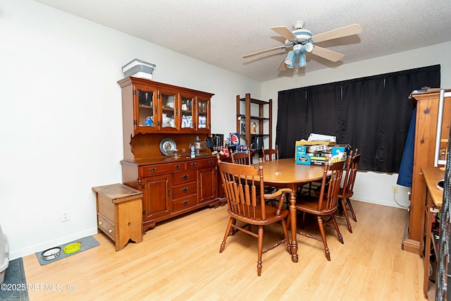 dining room with ceiling fan, a textured ceiling, and light wood-type flooring