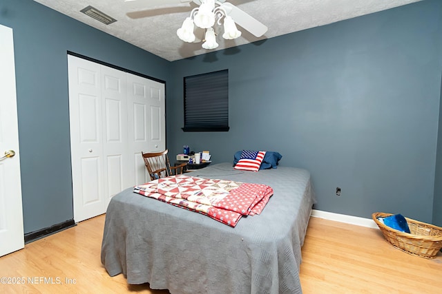 bedroom with hardwood / wood-style floors, ceiling fan, a textured ceiling, and a closet