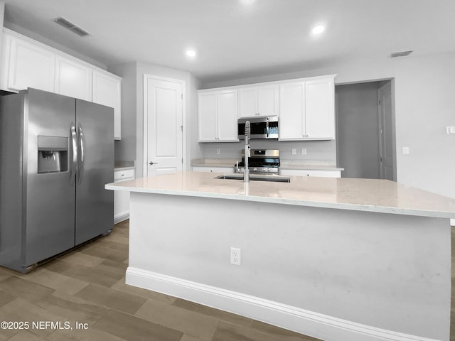 kitchen featuring sink, stainless steel appliances, white cabinetry, and a kitchen island with sink