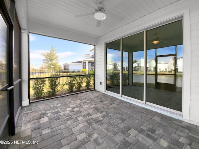 unfurnished sunroom with ceiling fan and a water view