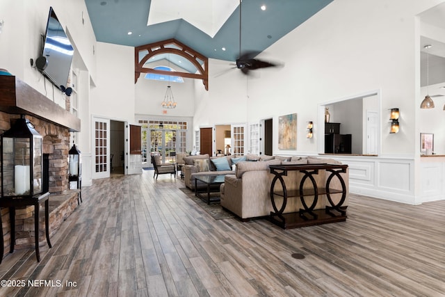 living room with ceiling fan, wood-type flooring, a high ceiling, and french doors