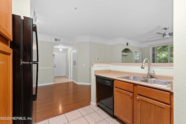 kitchen featuring crown molding, sink, light tile patterned floors, and black appliances