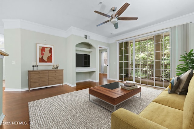 living room with built in shelves, ceiling fan, dark hardwood / wood-style flooring, and ornamental molding