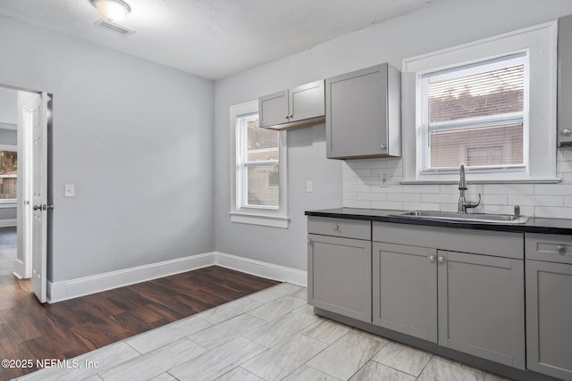 kitchen with gray cabinets, tasteful backsplash, a healthy amount of sunlight, and sink