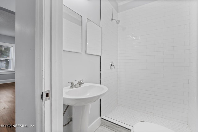 bathroom featuring tiled shower, hardwood / wood-style floors, and toilet