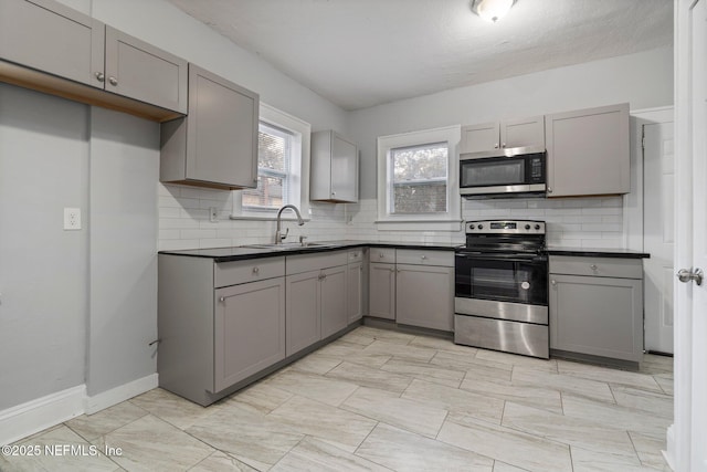 kitchen featuring backsplash, gray cabinets, sink, and appliances with stainless steel finishes