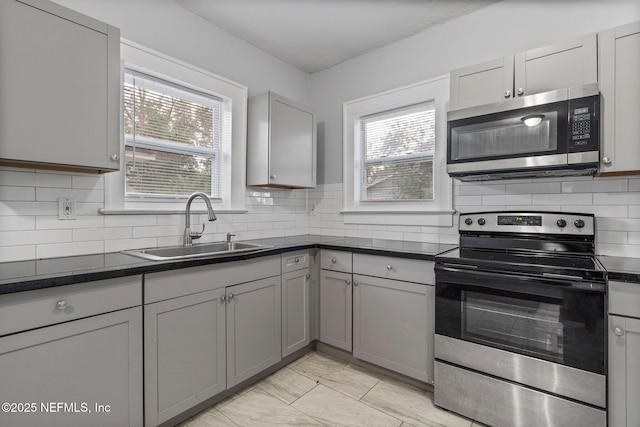 kitchen featuring gray cabinetry, a healthy amount of sunlight, sink, and stainless steel appliances