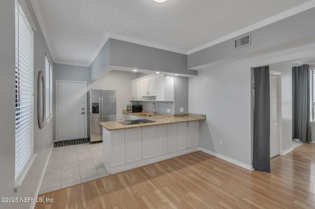 kitchen featuring kitchen peninsula, appliances with stainless steel finishes, light wood-type flooring, white cabinets, and ornamental molding