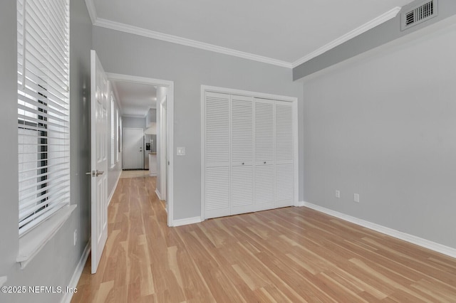 unfurnished bedroom featuring light hardwood / wood-style flooring, a closet, and crown molding