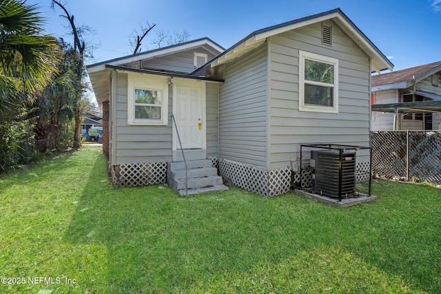 back of house with central AC unit and a yard