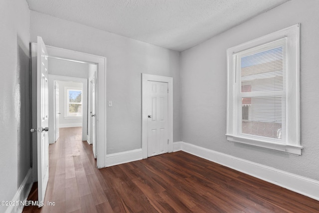 spare room featuring a textured ceiling and dark hardwood / wood-style flooring