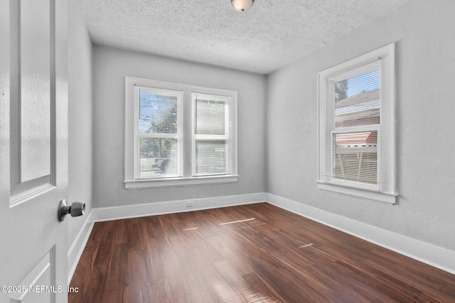 unfurnished room featuring a textured ceiling, a wealth of natural light, and dark hardwood / wood-style floors