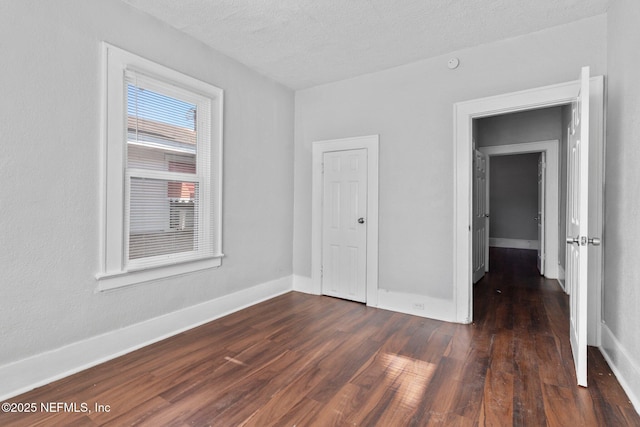 unfurnished bedroom with a textured ceiling and dark hardwood / wood-style floors